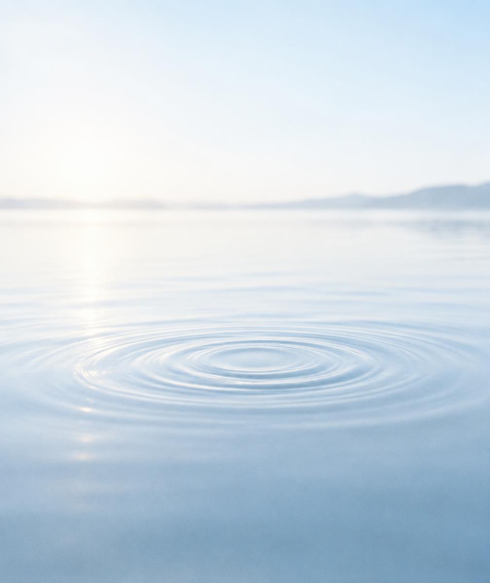 Still, pale blue water with a single set of gentle ripples